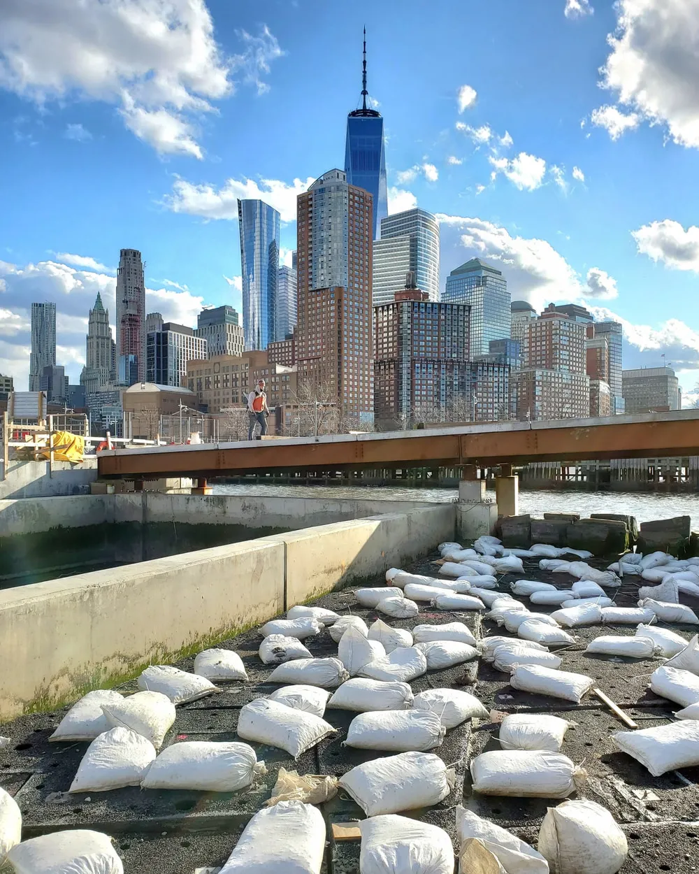 Electrical crew working on pier infrastructure on the Hudson River, Lower Manhattan skyline behind.